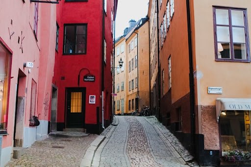 Smal kullerstensgata mellan färgglada historiska hus i Gamla Stan, Stockholm